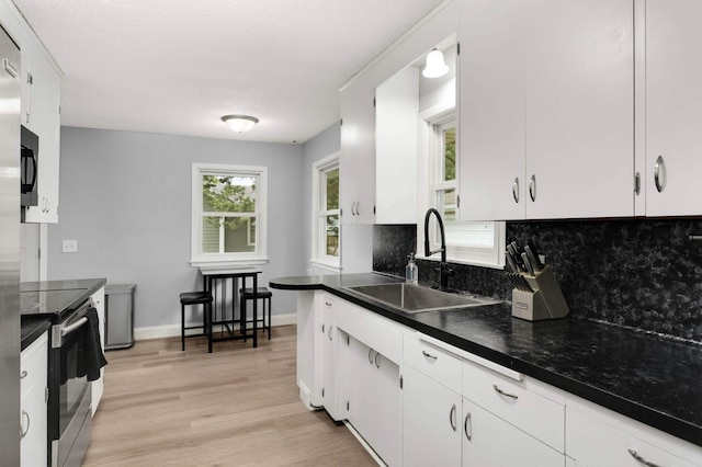 6719 Ewing Ave N, Brooklyn Center, MN 55429 - kitchen with stainless steel range with electric cooktop, a sink, decorative backsplash, dark countertops, and light wood finished floors