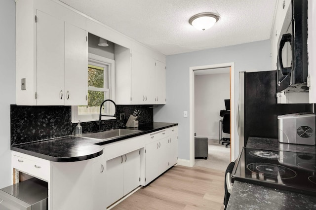 6719 Ewing Ave N, Brooklyn Center, MN 55429 - kitchen featuring a sink, dark countertops, black microwave, white cabinets, and a textured ceiling