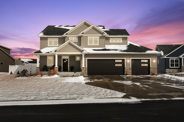 craftsman inspired home featuring board and batten siding, fence, covered porch, stone siding, and driveway