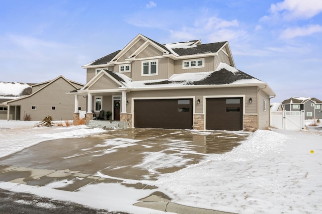 view of front of home featuring a gate, stone siding, fence, board and batten siding, and concrete driveway