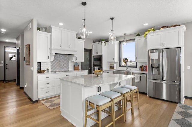 kitchen with a sink, stainless steel appliances, light wood-style flooring, and white cabinetry