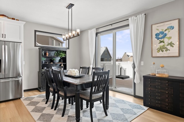 dining room with light wood-type flooring, baseboards, and a notable chandelier