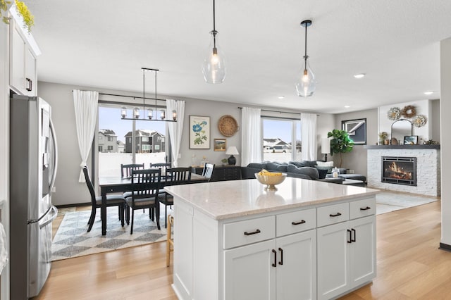 kitchen featuring stainless steel fridge, light wood-style floors, a center island, and white cabinetry