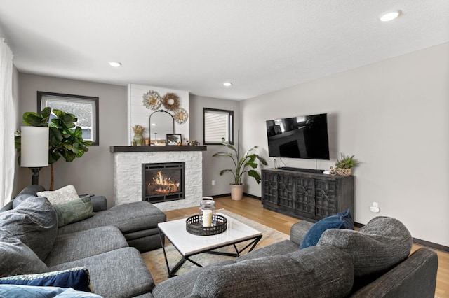 living room featuring recessed lighting, a stone fireplace, and wood finished floors