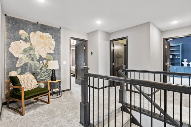 hall featuring carpet flooring, an upstairs landing, and baseboards