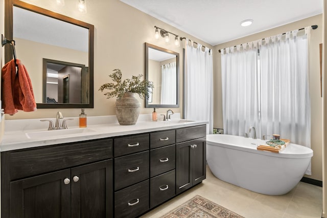 bathroom featuring a sink, a freestanding bath, double vanity, and tile patterned floors