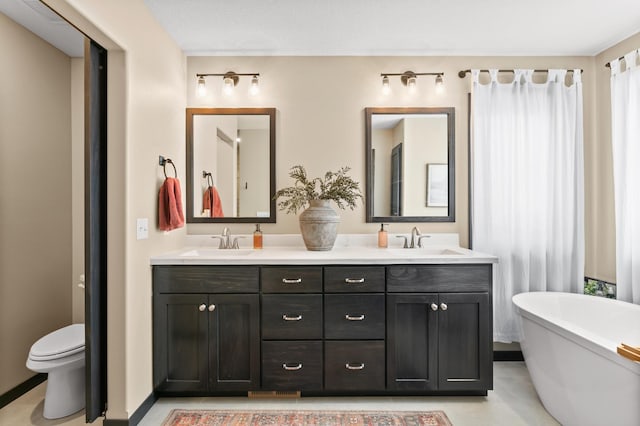 bathroom with a freestanding bath, double vanity, toilet, and a sink