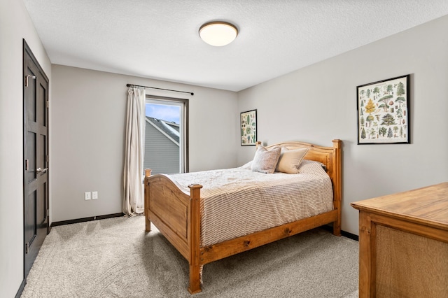 bedroom featuring light carpet, a textured ceiling, and baseboards