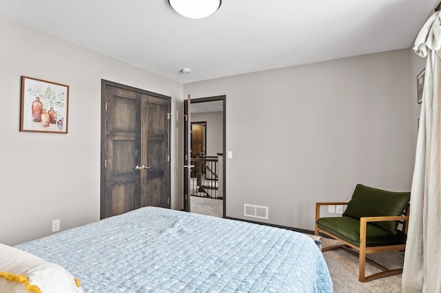 carpeted bedroom with visible vents, baseboards, and a closet