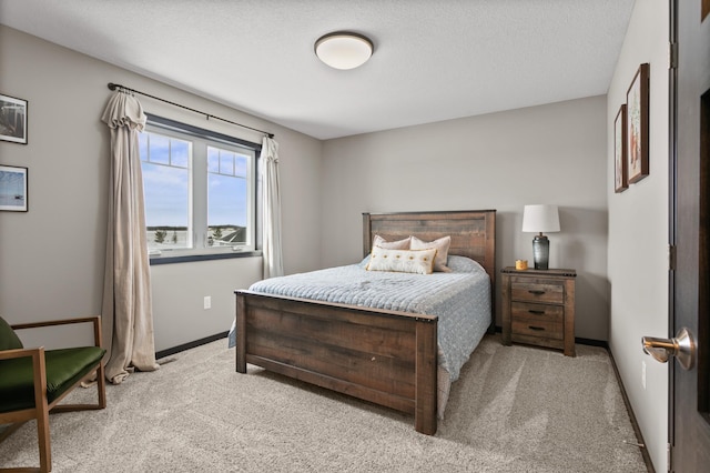 bedroom featuring light carpet, a textured ceiling, and baseboards