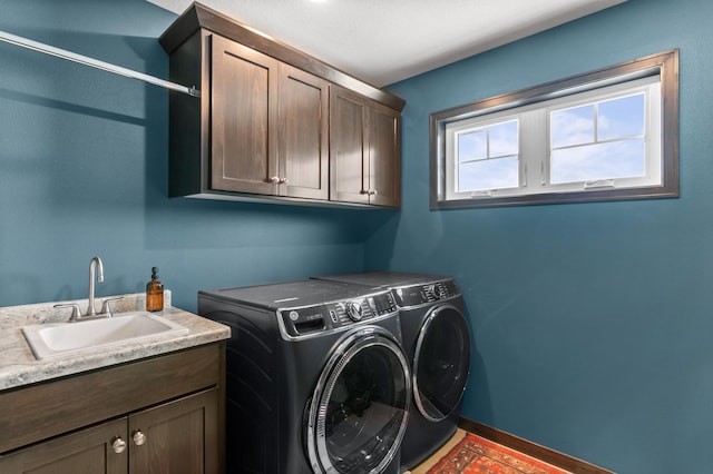 laundry room featuring washing machine and dryer, cabinet space, baseboards, and a sink