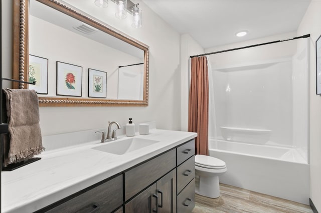 bathroom with vanity, wood finished floors, visible vents, toilet, and shower / tub combo with curtain