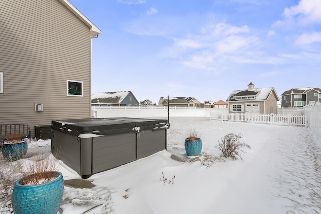 yard covered in snow with a fenced backyard, a residential view, and a hot tub