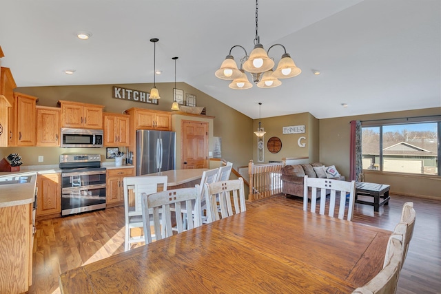 dining area with lofted ceiling, a notable chandelier, and light wood-style floors