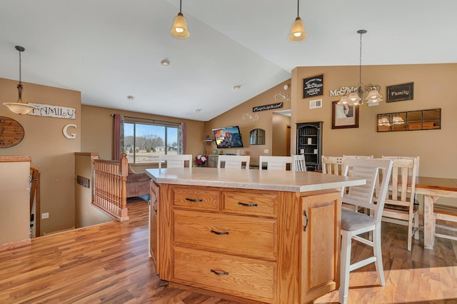 kitchen with light wood finished floors, vaulted ceiling, light countertops, and a center island