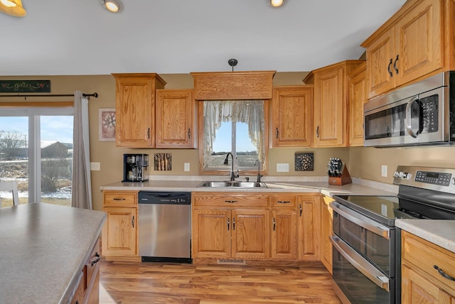 kitchen with light wood-style flooring, appliances with stainless steel finishes, light countertops, and a sink