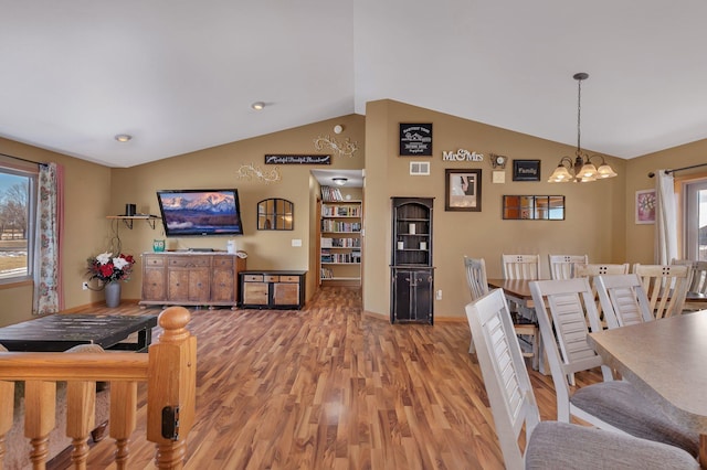 dining space featuring a chandelier, visible vents, vaulted ceiling, and light wood-style flooring