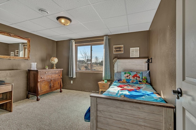 bedroom with carpet, a drop ceiling, and a textured wall