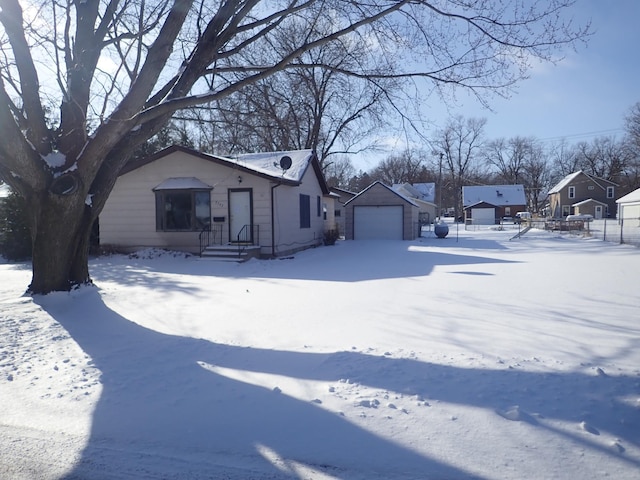 snowy yard with a garage, a residential view, and an outbuilding