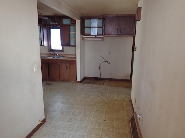 kitchen featuring light floors, visible vents, baseboards, and a sink