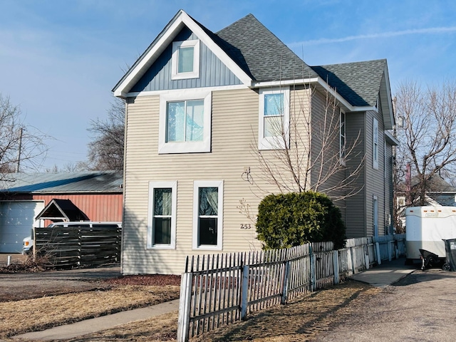 view of front of home featuring board and batten siding, a fenced front yard, and roof with shingles