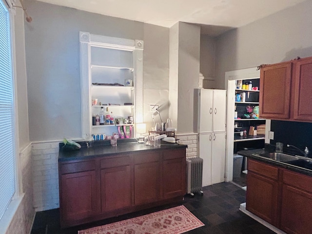 kitchen featuring dark countertops, radiator, brown cabinets, and a sink