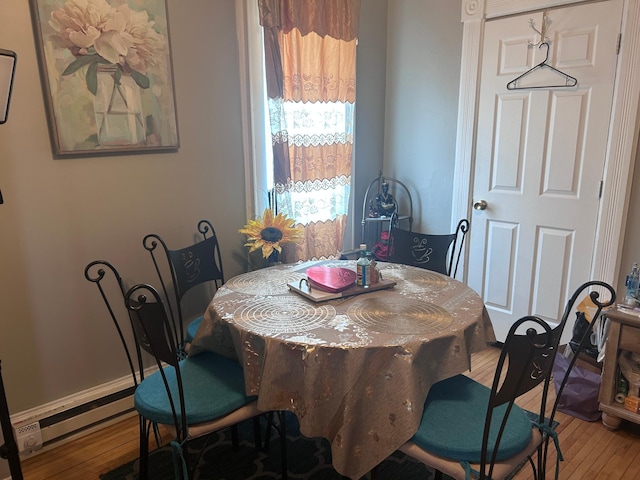 dining space featuring hardwood / wood-style floors, baseboards, and a baseboard heating unit