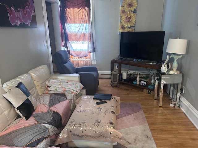 living area with baseboard heating, baseboards, and wood finished floors