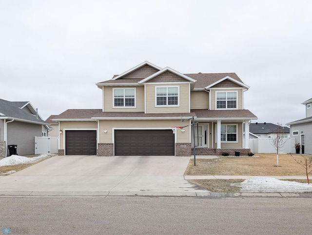 craftsman house featuring brick siding, a gate, fence, a garage, and driveway