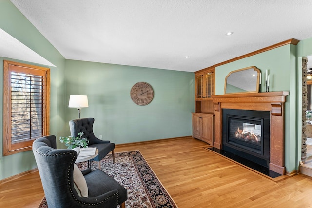 living area featuring a fireplace with flush hearth, recessed lighting, baseboards, and light wood finished floors