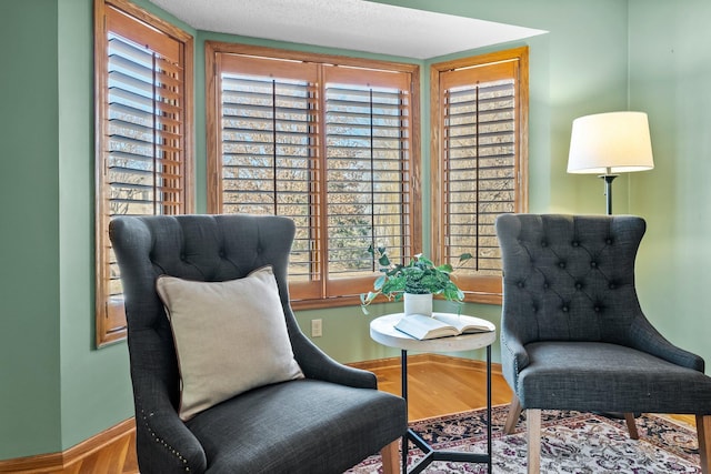 sitting room with baseboards and wood finished floors