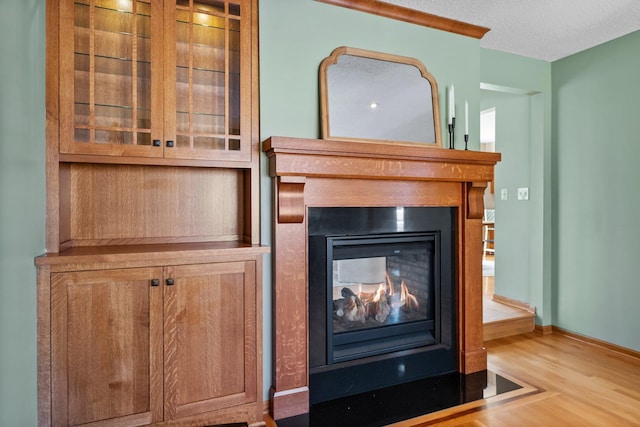 interior details featuring baseboards, a multi sided fireplace, a textured ceiling, and wood finished floors