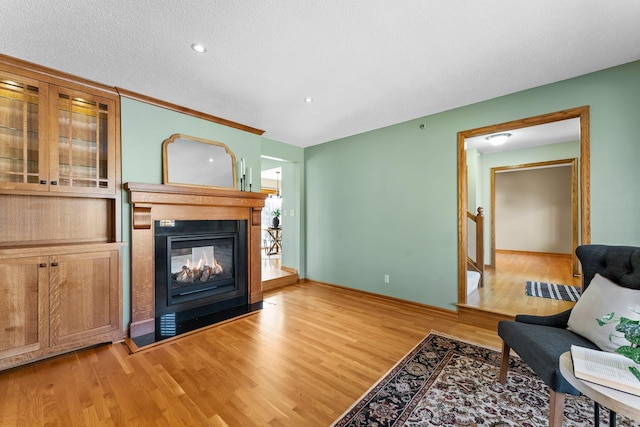 living area featuring baseboards, a multi sided fireplace, light wood-style floors, and a textured ceiling