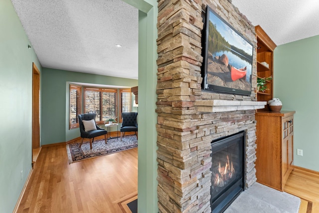 interior space featuring baseboards, a textured ceiling, wood finished floors, and a fireplace