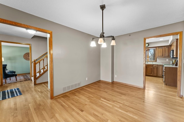 dining area featuring visible vents, baseboards, light wood-style floors, and stairway