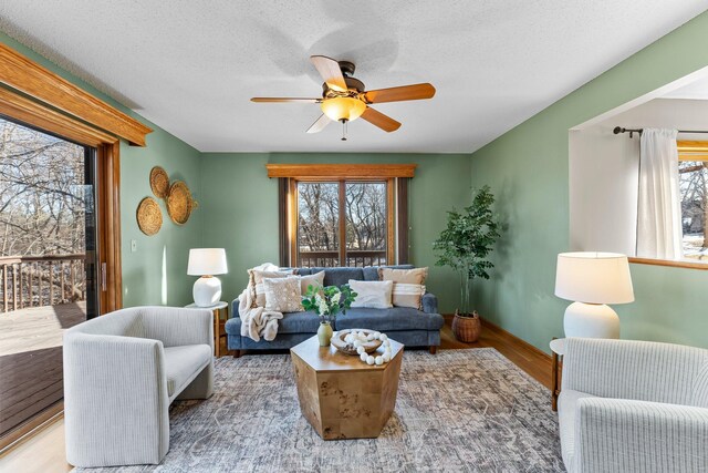 living room featuring a healthy amount of sunlight, a textured ceiling, ceiling fan, and wood finished floors