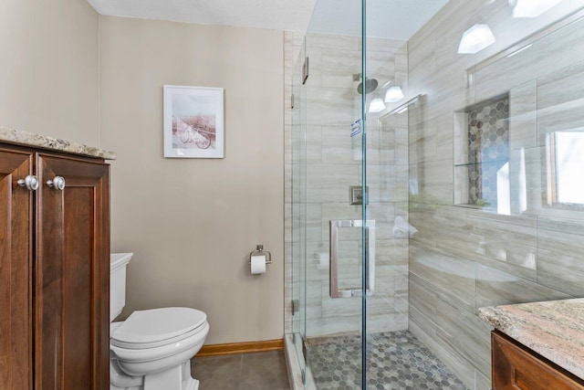 bathroom with vanity, tile patterned floors, toilet, and a stall shower