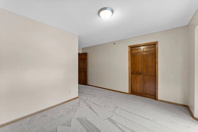 spare room featuring baseboards and light colored carpet