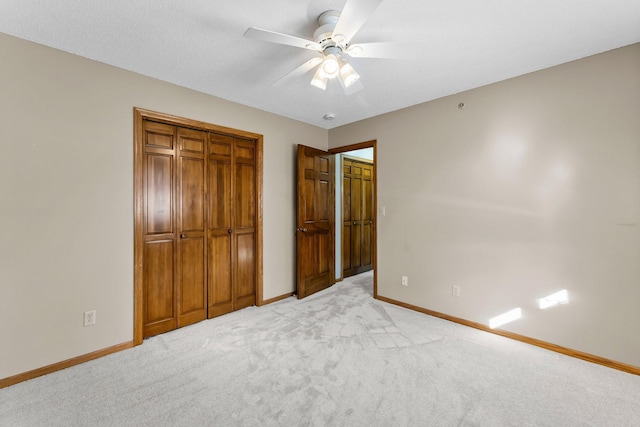 unfurnished bedroom featuring a closet, light carpet, baseboards, and a ceiling fan