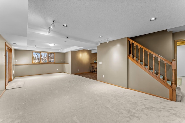 interior space with track lighting, baseboards, carpet, stairs, and a textured ceiling