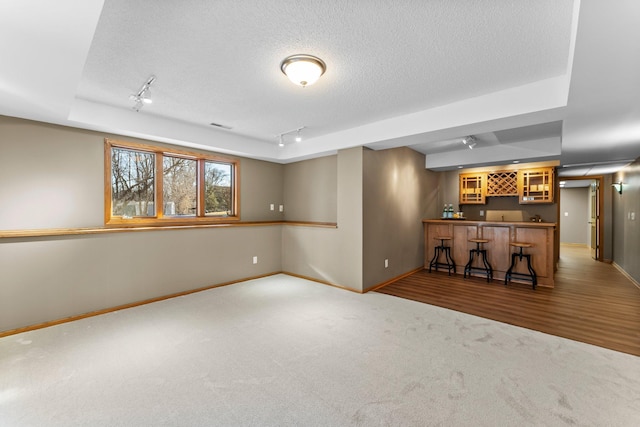 interior space featuring indoor wet bar, rail lighting, baseboards, and a textured ceiling