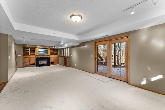 unfurnished living room with baseboards, carpet floors, a textured ceiling, and a glass covered fireplace