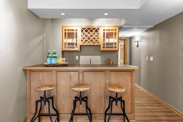 bar with recessed lighting, indoor wet bar, baseboards, and wood finished floors