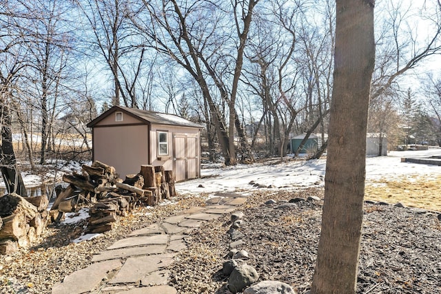 yard covered in snow featuring a storage unit and an outdoor structure