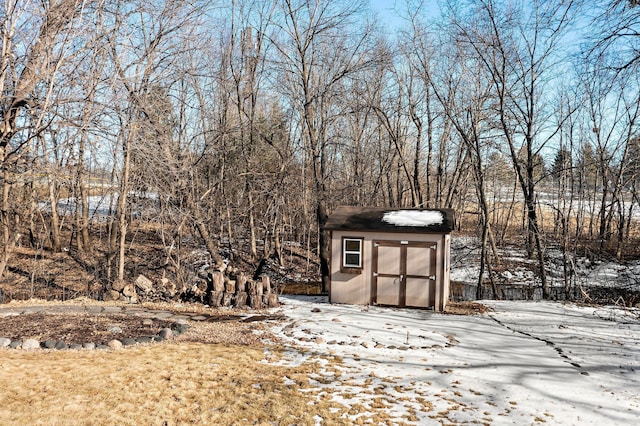 snow covered structure featuring an outbuilding and a storage shed