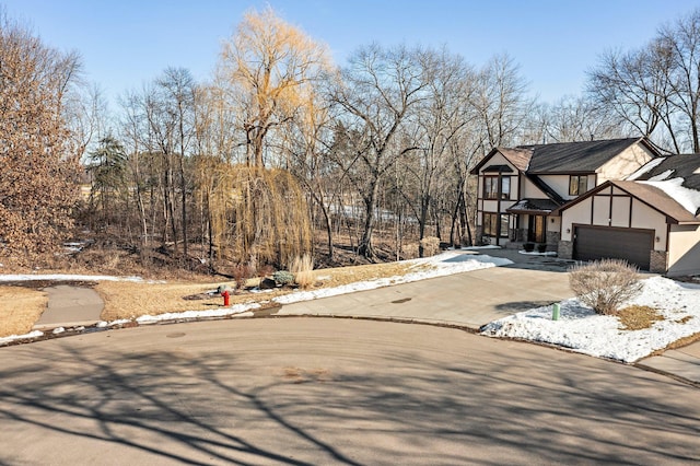 view of front facade with stone siding, driveway, and stucco siding