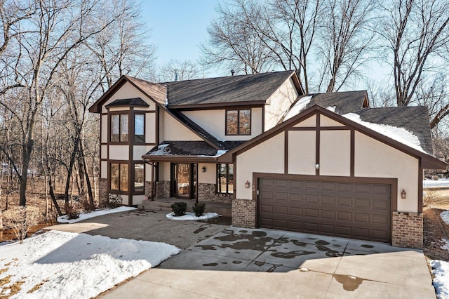 tudor-style house with concrete driveway, brick siding, a garage, and stucco siding