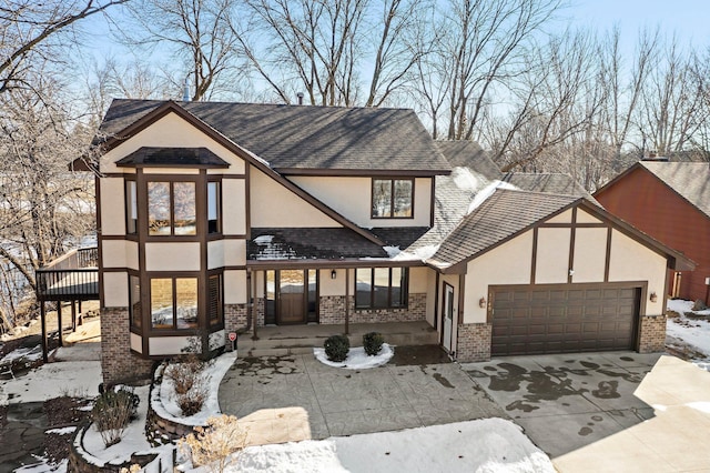 tudor home with concrete driveway, a garage, brick siding, and stucco siding