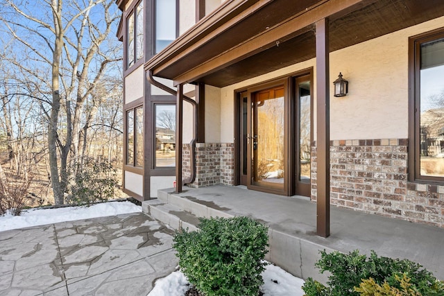 doorway to property with stucco siding and brick siding