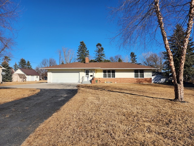 ranch-style house with a garage, brick siding, driveway, a chimney, and a front yard